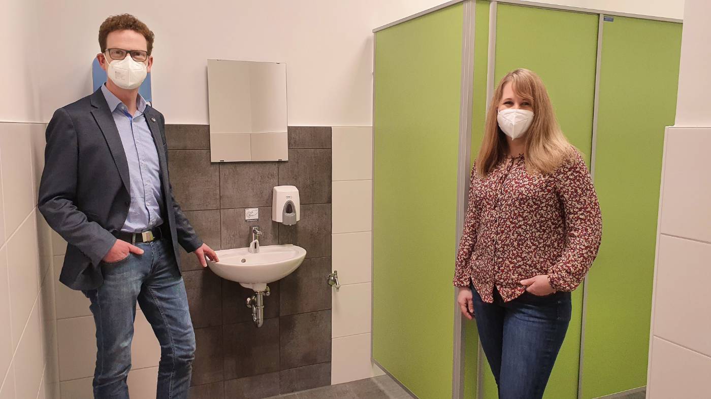 v.l.n.r.: Schulleiter Markus Gille und Bauingenieurin Melanie Weiershäuser freuen sich über die neu sanierte Toilettenanlage an der Radko-Stöckl-Schule
