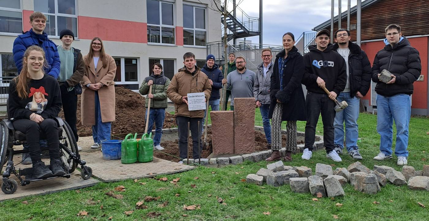 Die Lerngruppe Fachoberschule Wirtschaft und Verwaltung (12A061) freut sich über die gemeinsame Pflanzung des Gedenkbaums mit Landschaftsgartenbauer Johannes Trieschmann (Bildmitte)