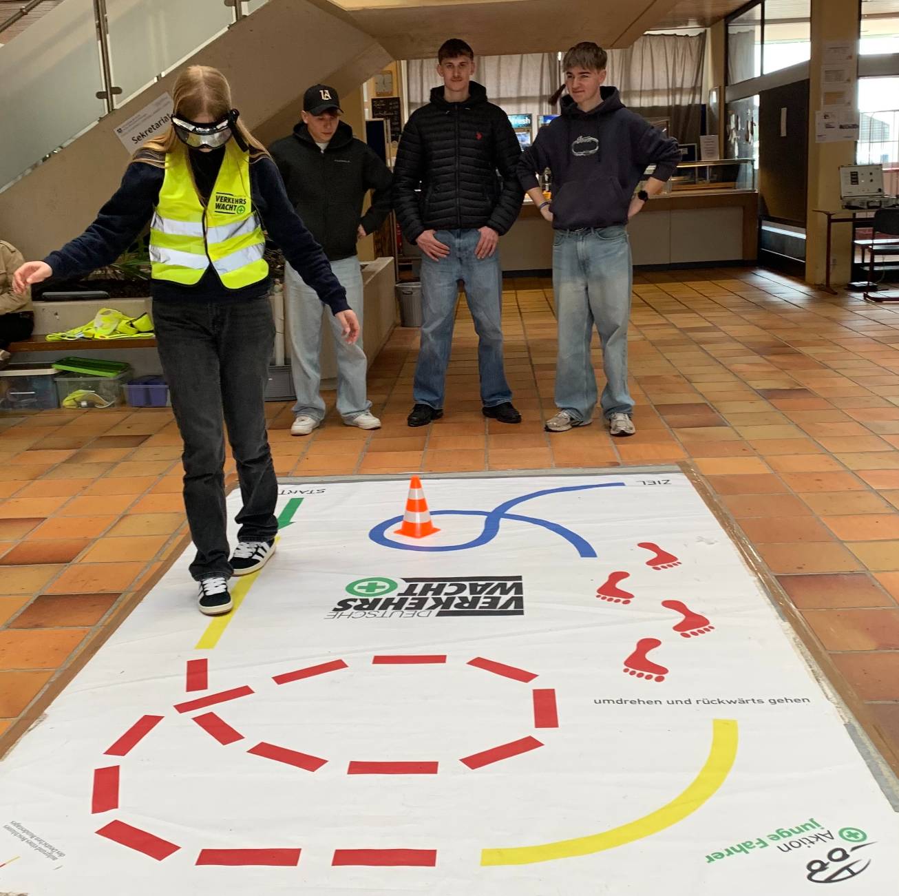 Angelina Pfeifer aus der 11A132 bei der Erprobung der Rauschbrille.  Im Hintergrund die Mitschüler Fynn Brinker, Luca Knieling und Lukas Ehmer.